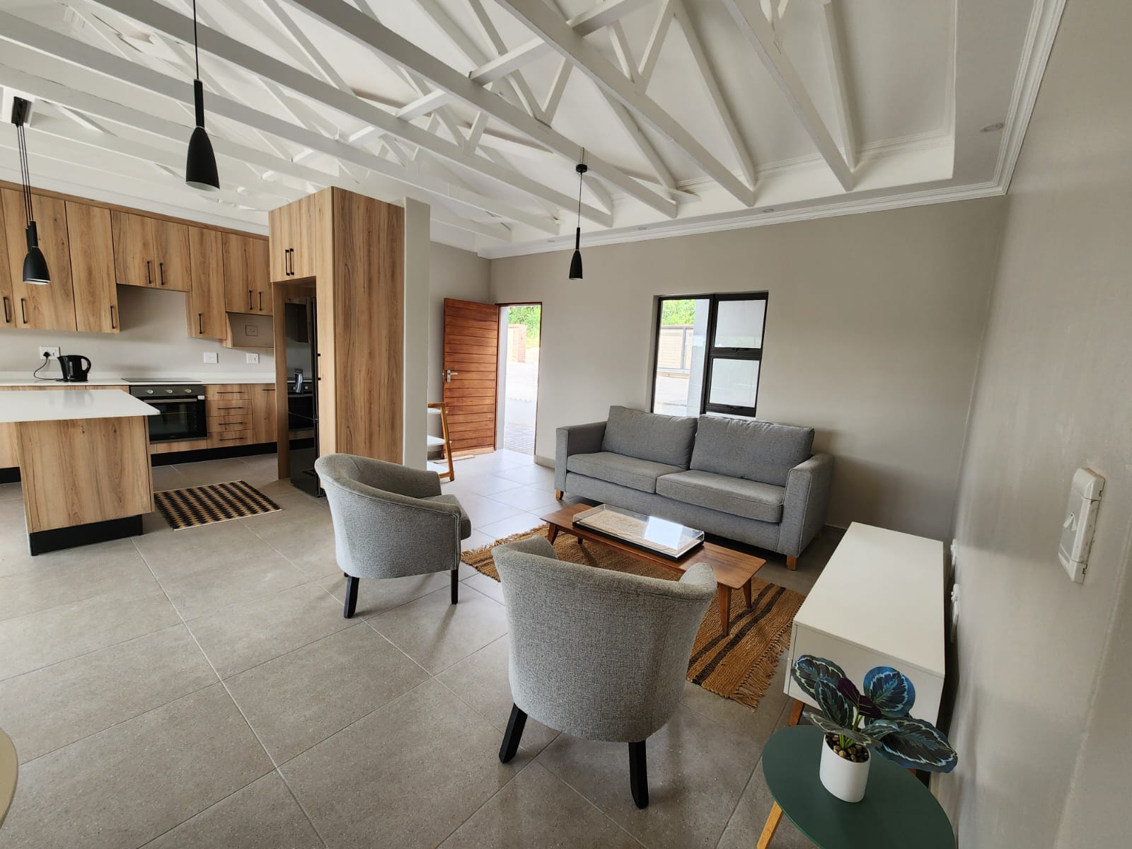 Open-plan living area and kitchen with exposed roof trusses