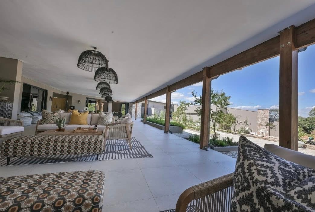 Covered veranda lounge at White River Manor with wicker pendant lights and views across the landscaped grounds