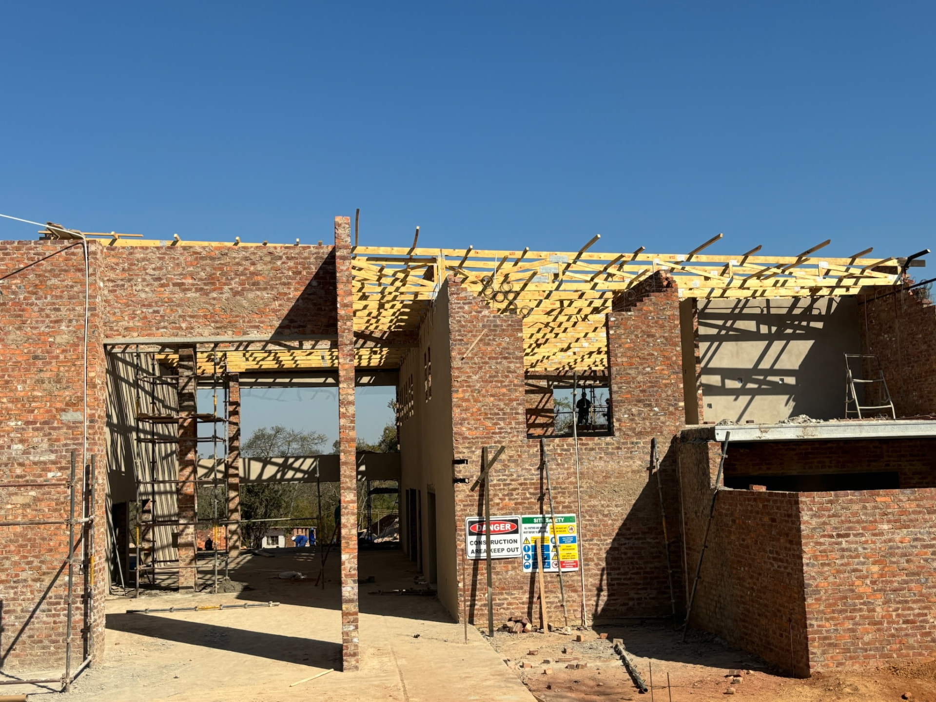 Face brick structure under construction with timber roof trusses installed