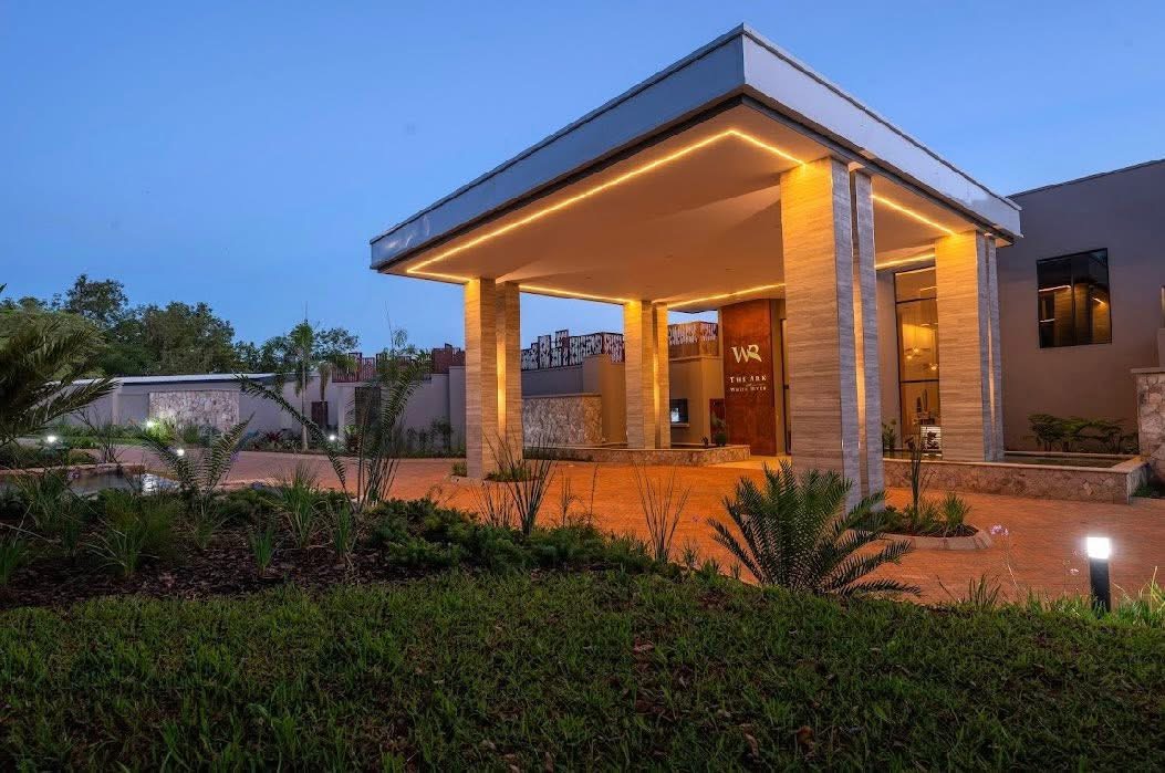 Stone-clad entrance canopy and drop-off driveway at White River Manor photographed at dusk, with lawn and native planting in the foreground
