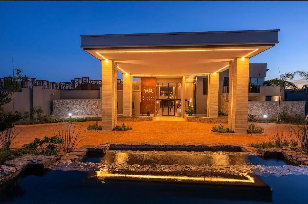 White River Manor entrance canopy at dusk seen across a tiered stone water feature and paved drop-off driveway