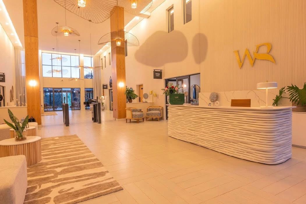 Reception lobby at White River Manor with a white fluted reception desk, timber-wrapped columns and woven pendant lights