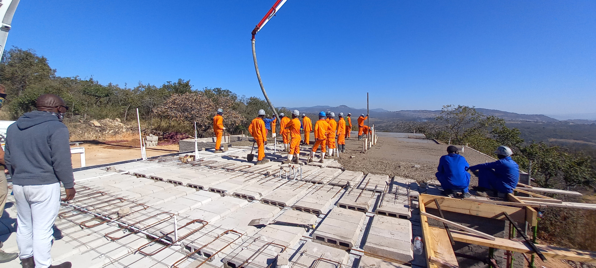 Construction team pouring a suspended concrete slab with pump on a hilltop site