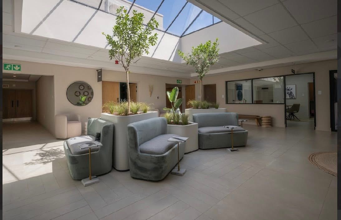 Daylit interior atrium at White River Manor with planter boxes, small trees and curved bench seating beneath a skylight