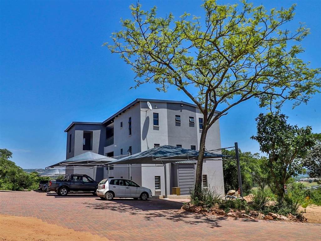Apartment block with covered parking bays and landscaped paving