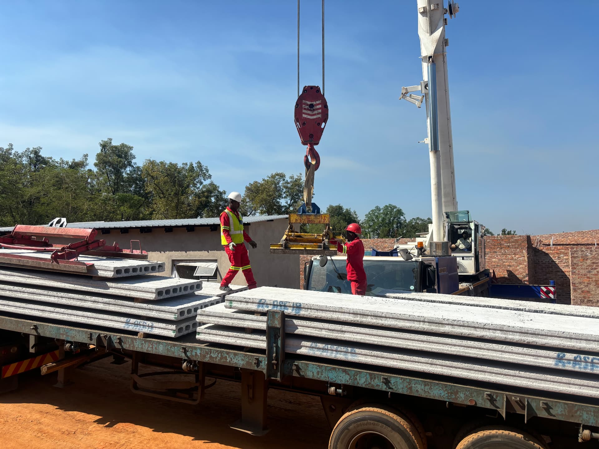 Mobile crane offloading hollow-core concrete planks from a flatbed truck
